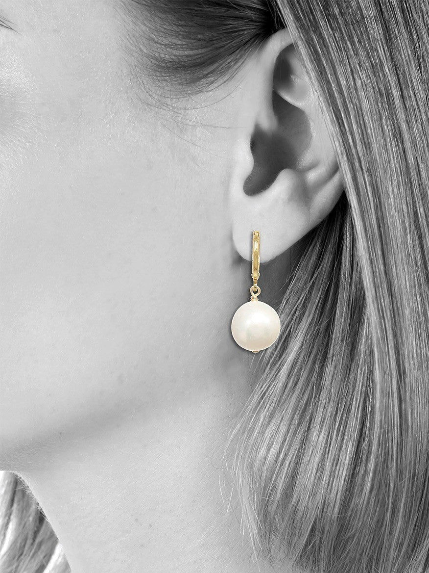 A woman wearing a Margo Morrison Small White Baroque Pearl Earring.