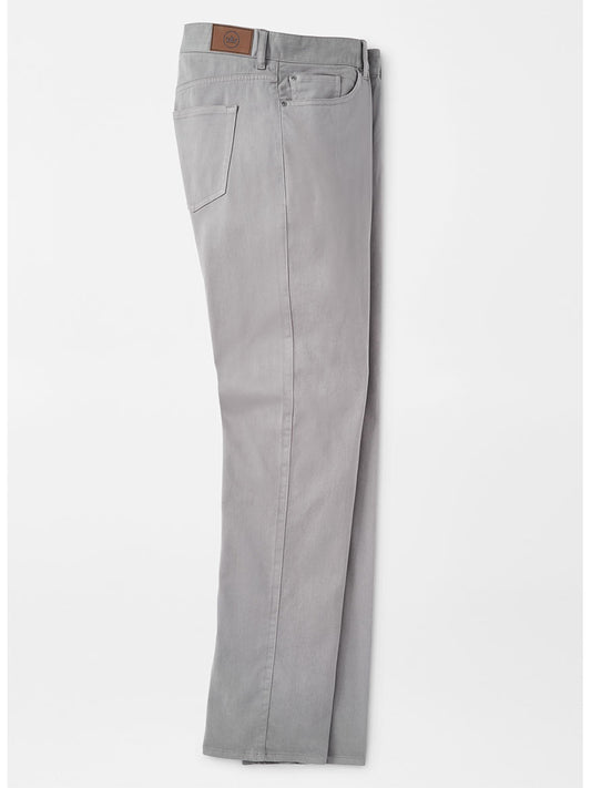 A pair of Peter Millar Ultimate Sateen Five-Pocket Pant in Gale Grey with a Peter Millar leather patch on the waistband folded and laid flat on a white background.