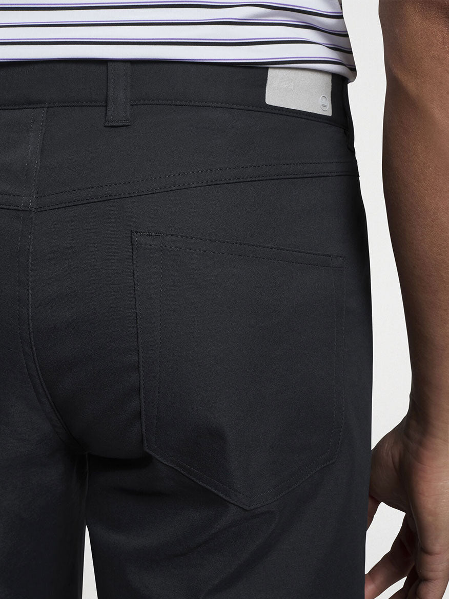 A person is shown from the waist down wearing Peter Millar Performance Five-Pocket Pant in Black and a white and black striped shirt.