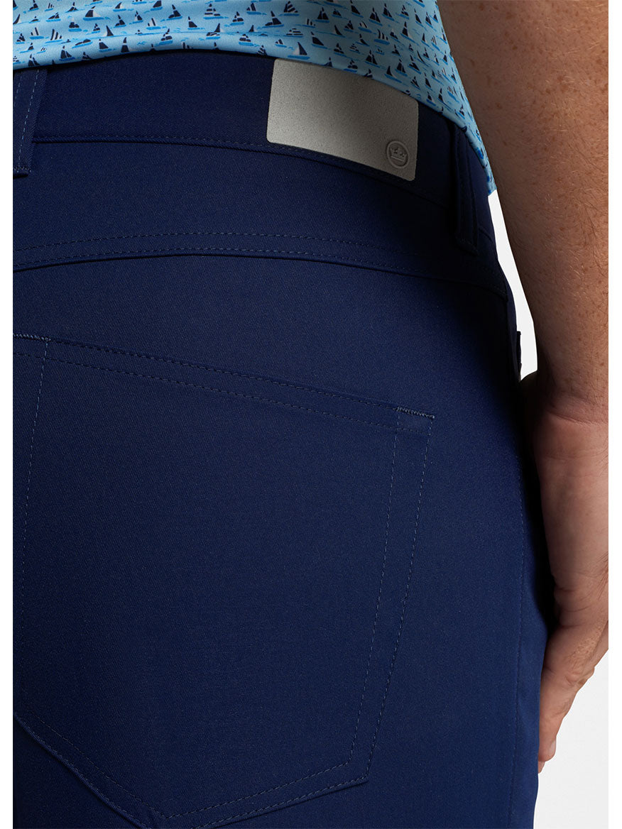 Close-up of the back pocket area of a person wearing Peter Millar Performance Five-Pocket Pant in Navy with a two-way stretch and a light blue shirt with a nautical pattern, just like you'd see on PGA Tour players.