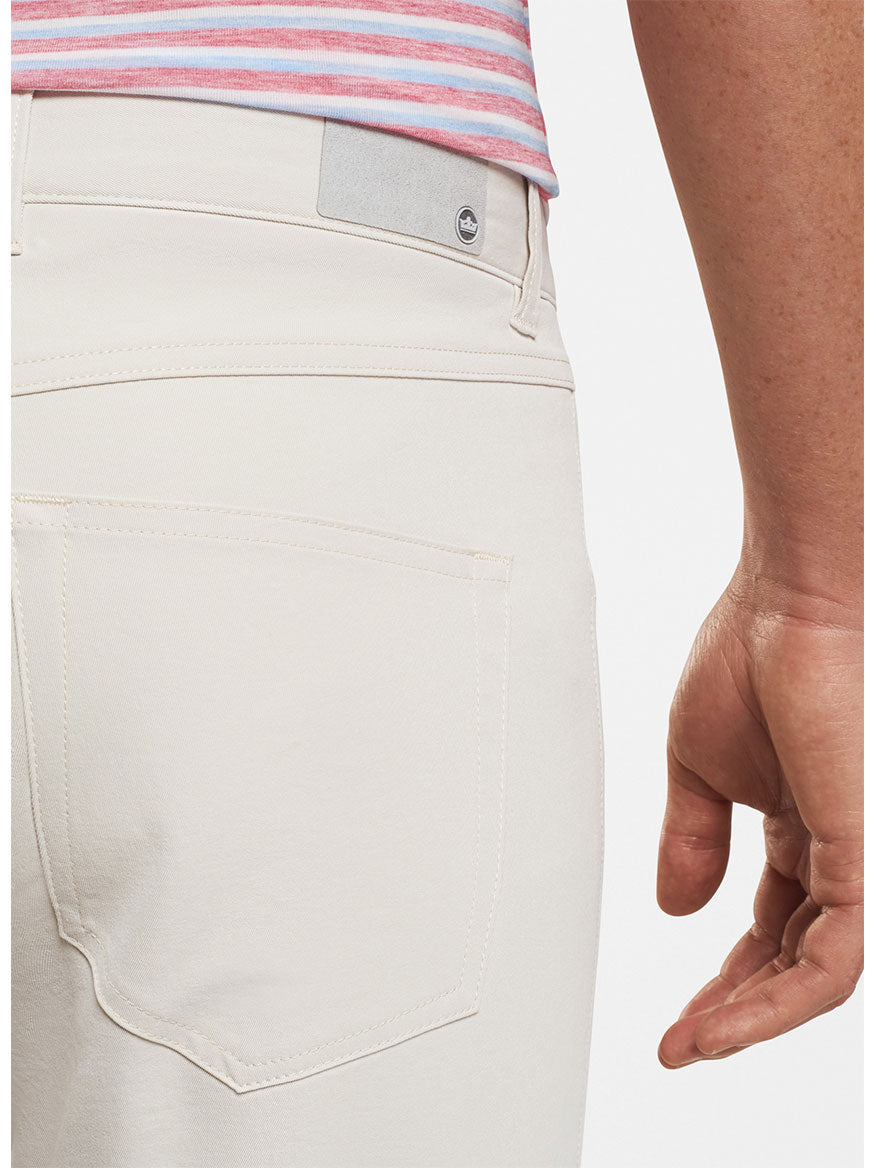 Close-up of a person's side wearing Peter Millar Performance Five-Pocket Pant in Stone, focusing on the pocket detail and waistband with a button visible.
