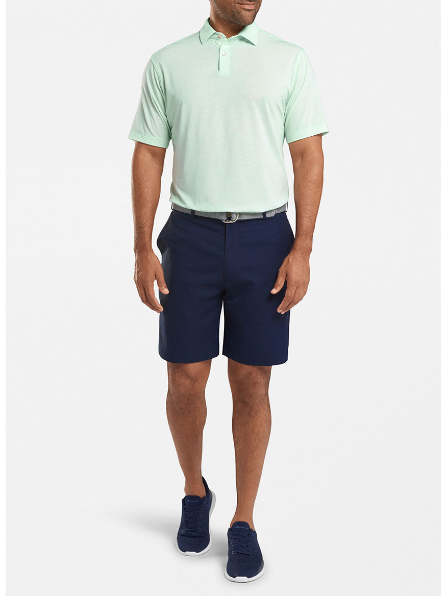 A person in a light green polo shirt, Peter Millar Salem Performance Short in Navy, and navy sneakers stands against a plain white background. The quick-dry fabric ensures comfort all day long.