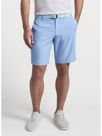 Man wearing the Peter Millar Salem High Drape Performance Short in Cottage Blue and white sneakers.