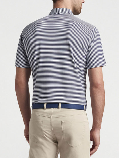 Man wearing a Peter Millar Hales Performance Jersey Polo in Navy and beige pants with a blue belt, viewed from behind.