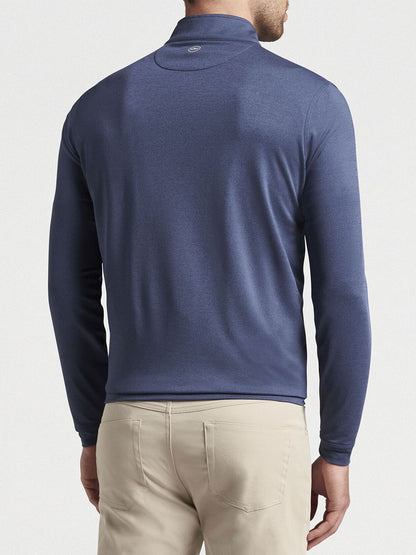 A man wearing a navy blue Peter Millar Perth Melange Performance Quarter-Zip sweater and beige trousers, viewed from the back.