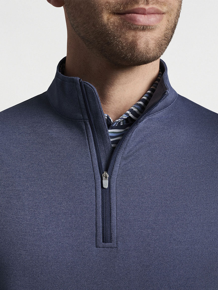 Close-up of a man wearing a navy blue Peter Millar Perth Melange Performance Quarter-Zip sweater over a striped shirt, focusing on the collar area.