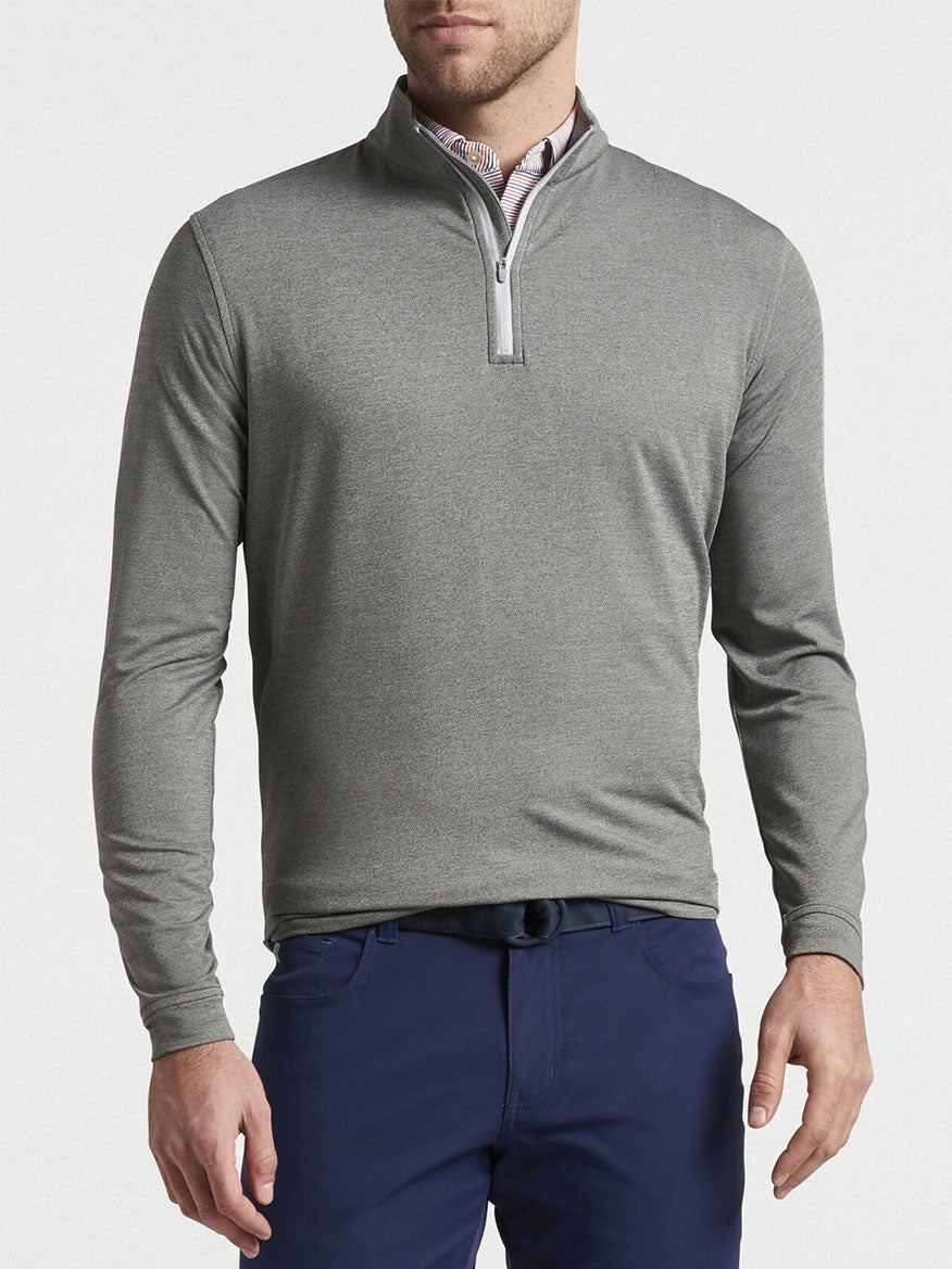 Man wearing a gray Peter Millar Perth Melange Performance Quarter-Zip in Smoke and blue trousers.