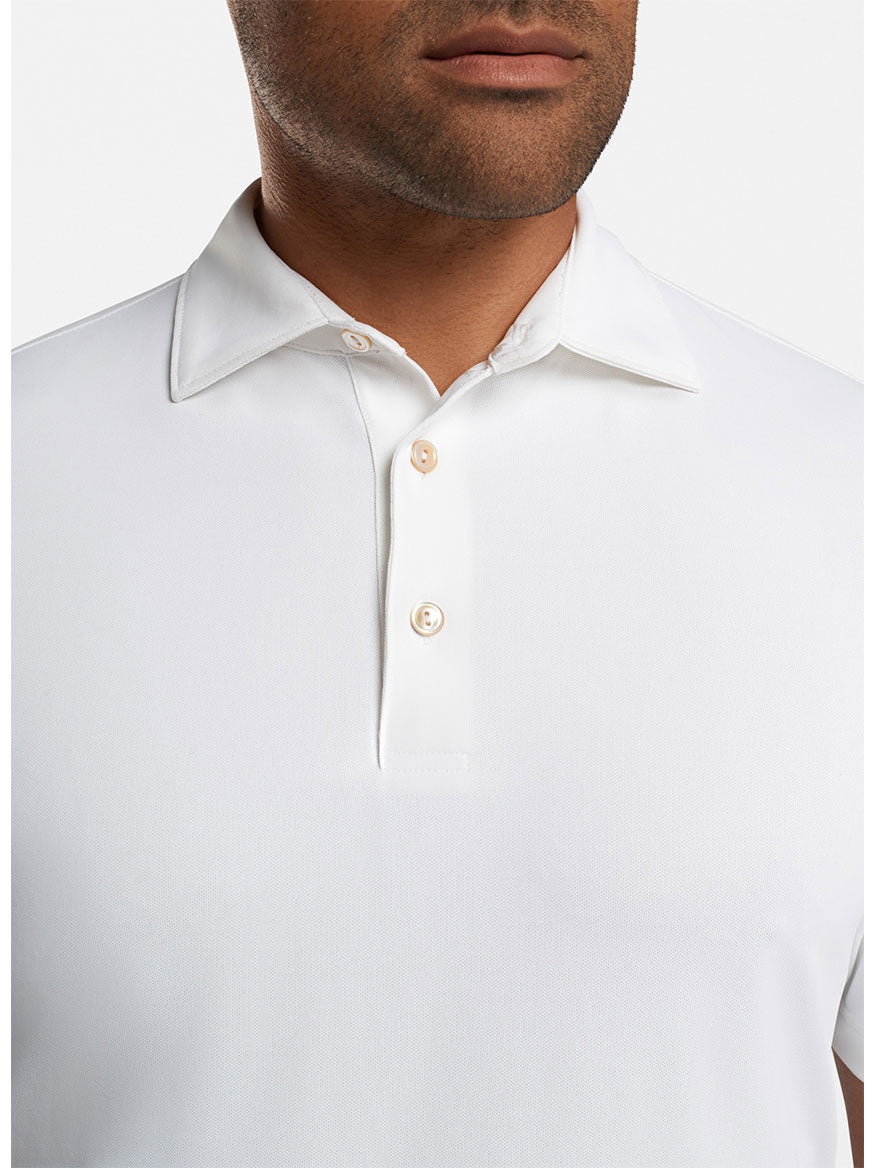 A man wearing the Peter Millar Solid Performance Mesh Polo in White, featuring a moisture-wicking fabric and three buttons, shown from the shoulders to just above the chin.