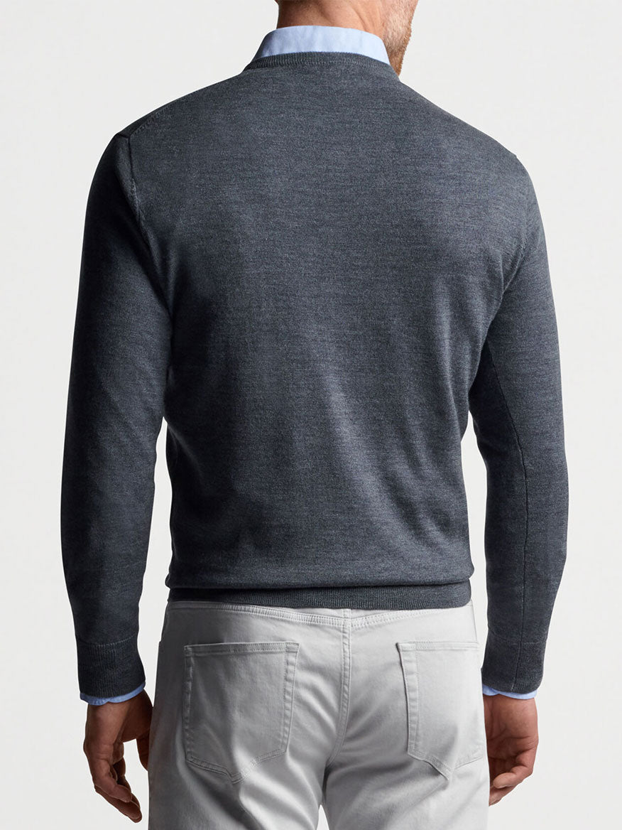The back view of a man wearing a grey Peter Millar Autumn Crest V-Neck in Charcoal sweater and white pants.