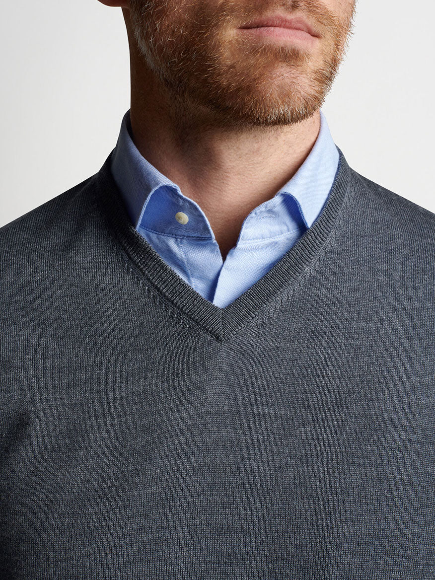 Peter Millar Autumn Crest V-Neck in Charcoal sweater made of Merino wool, paired with a blue shirt.