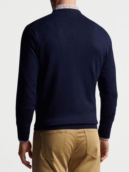 The back view of a man wearing a Peter Millar Autumn Crest V-Neck in Navy sweater and khaki pants, emphasizing its softness.