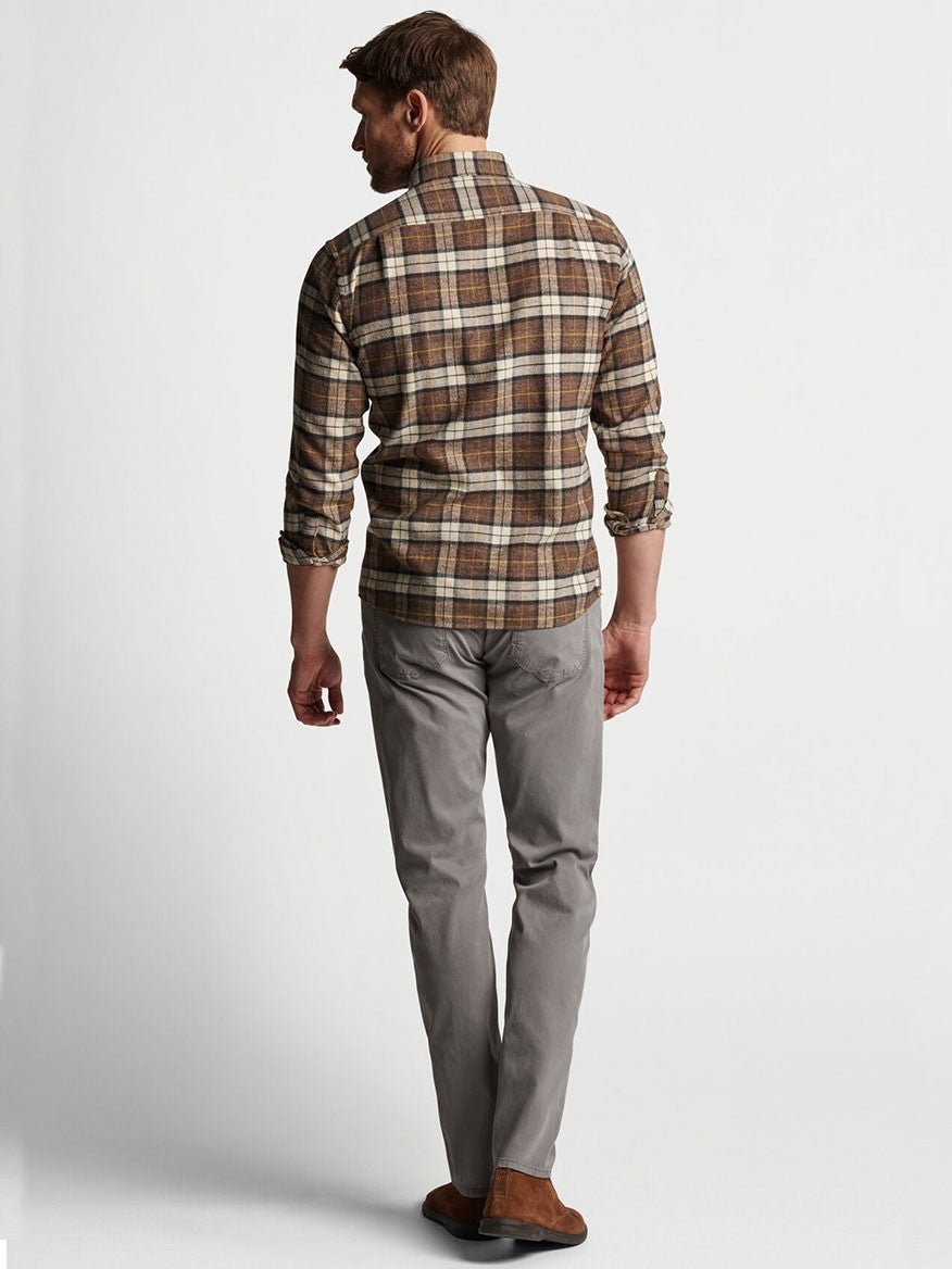 Man wearing a plaid shirt and garment-dyed Peter Millar Wayfare Five-Pocket Pant in Nickel from a rear view.