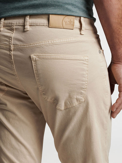 Close-up of a person wearing beige, garment-dyed Peter Millar Wayfare Five-Pocket pants in Stone with a detailed view of the back pocket and waistband.