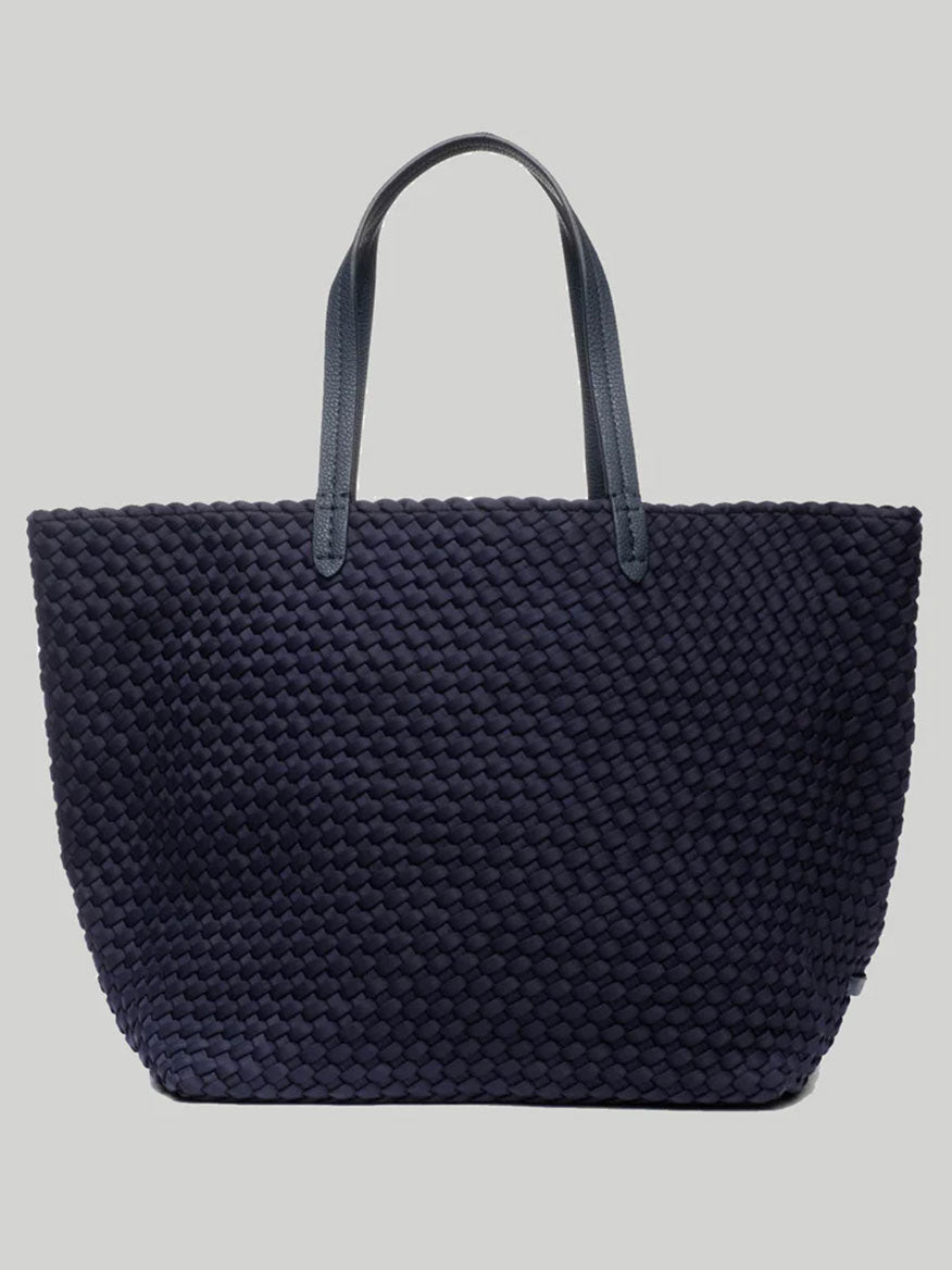 The Naghedi Jetsetter Large Tote in Solid Ink Blue, featuring a spacious design and black handles, is showcased on a plain background, making it perfect for travel adventures.