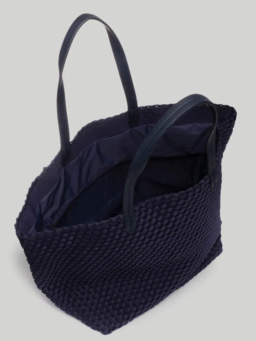 A Naghedi Jetsetter Large Tote in Solid Ink Blue, featuring a textured design with two black handles, showcased from a top angle on a neutral background, is perfect for travel.