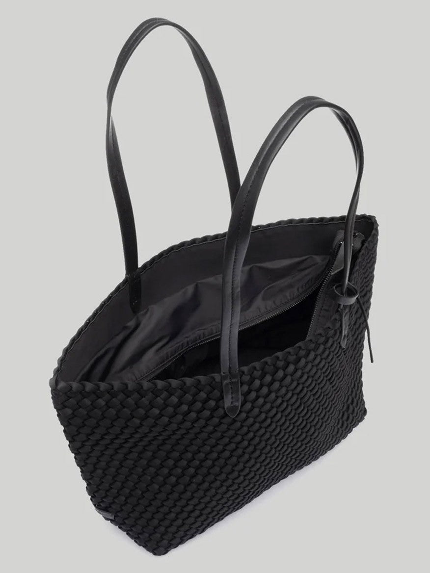 Naghedi Jetsetter Small Tote in Solid Onyx handwoven neoprene tote bag with long handles and an open top, showing a glimpse of its inner black lining.