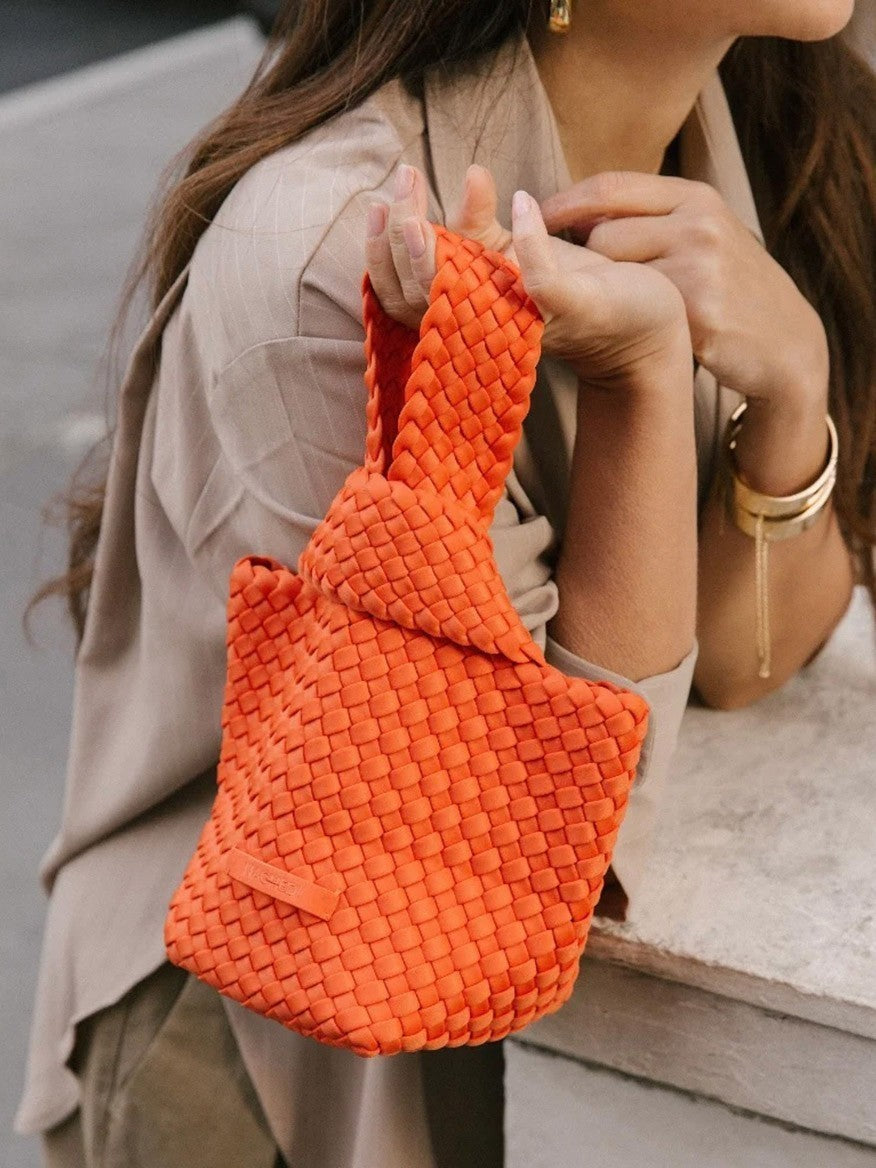 A woman carrying a Naghedi Kyoto Clutch in Solid Onyx on her shoulder.