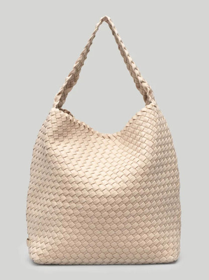 Solid Ecru woven neoprene Naghedi Nomad hobo bag with a braided strap on a plain gray background.