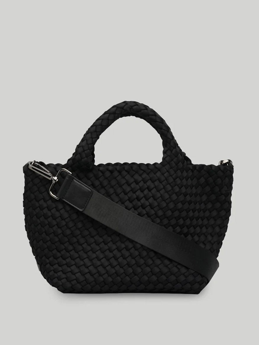 A chic and compact Naghedi St. Barths Small Tote in Solid Onyx featuring a black woven design with short handles, an adjustable shoulder strap, and a detachable crossbody strap, set against a plain light grey background.