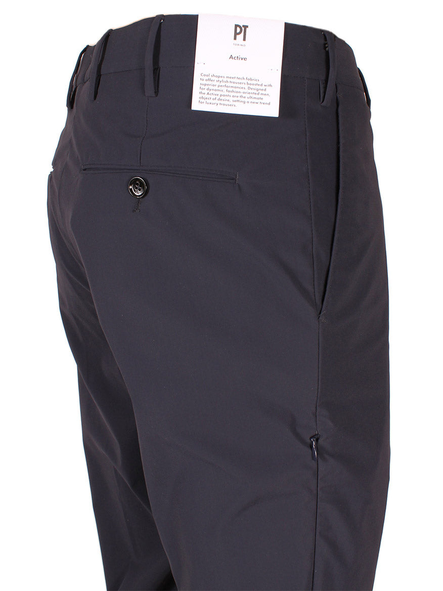 Rear view of stylish, slim fit black pants with a single back pocket, displaying a white tag labeled "PT01 Kinetic Active Lux Trouser in Navy" near the waistband.