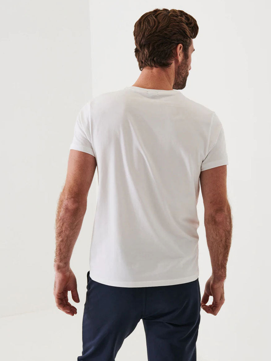 Man in a Patrick Assaraf Iconic T-Shirt in white and navy pants, standing with his back to the camera against a plain white background.