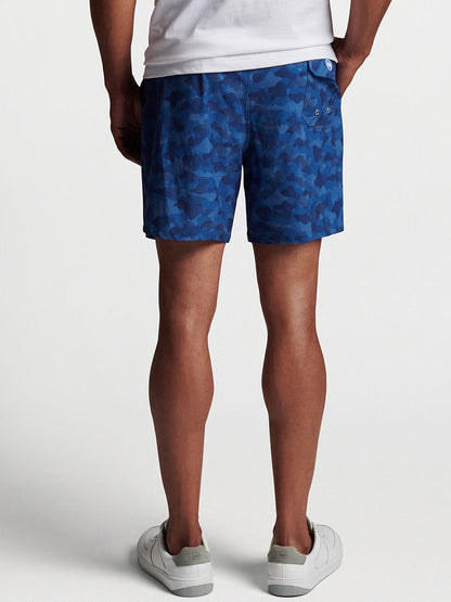 Man wearing blue patterned Peter Millar Camouflaged Coastline Swim Trunk in Navy and white sneakers.