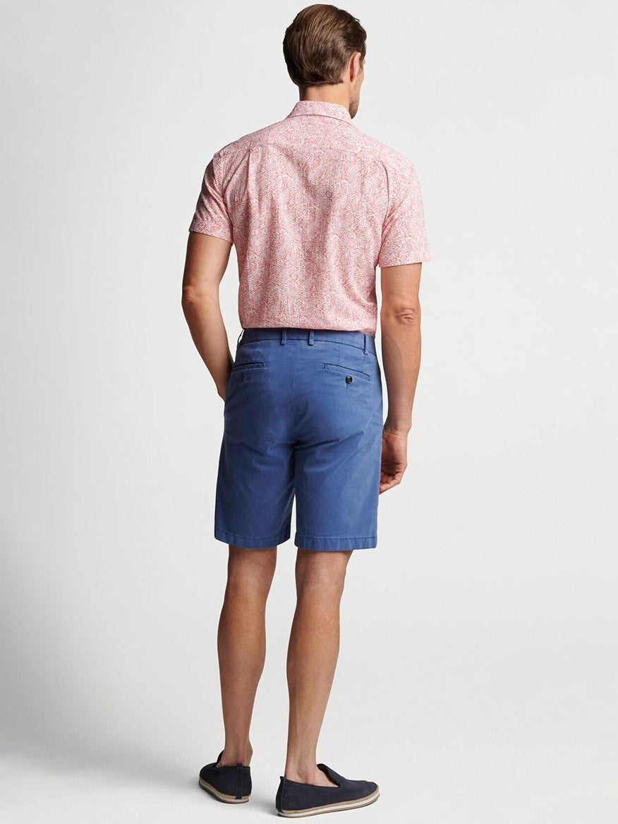 Man wearing a short-sleeve button-up shirt and Peter Millar Concorde Garment-Dyed Shorts in Riviera Blue standing with his back to the camera.
