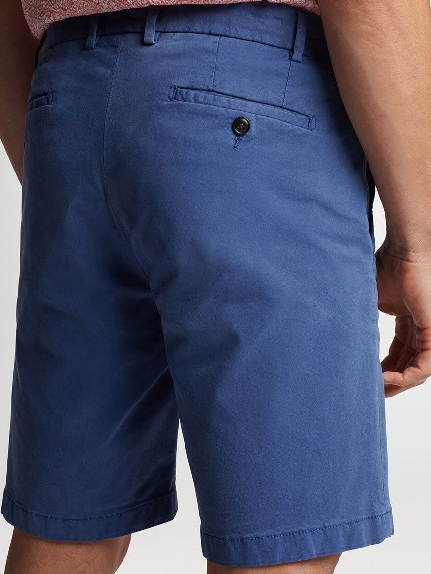 A close-up of a person wearing Peter Millar Concorde Garment-Dyed Shorts in Riviera Blue with a buttoned back pocket.