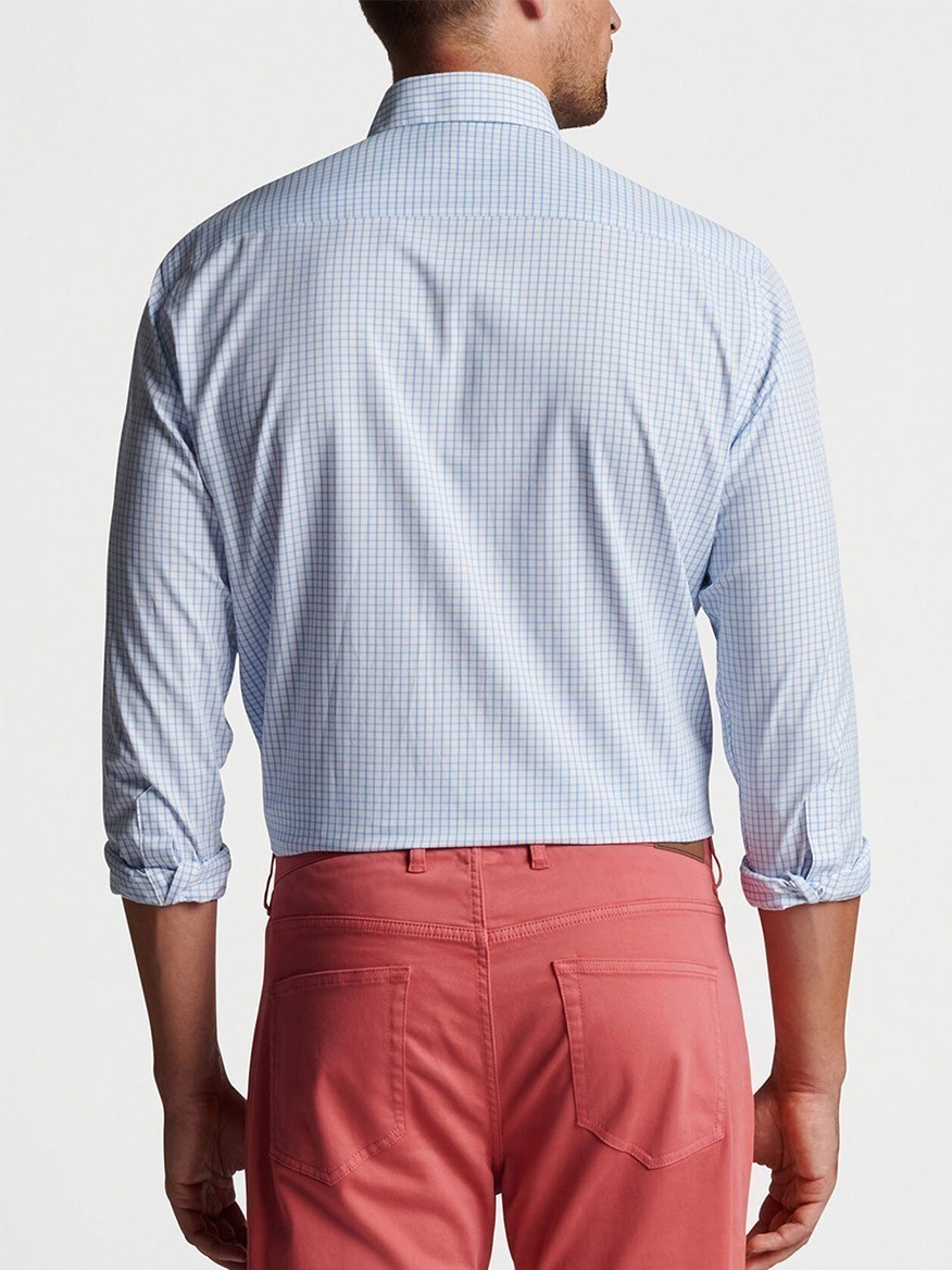 A man viewed from behind wearing a Peter Millar Hanford Performance Twill Sport Shirt in Cottage Blue and red trousers, exuding a performance style.