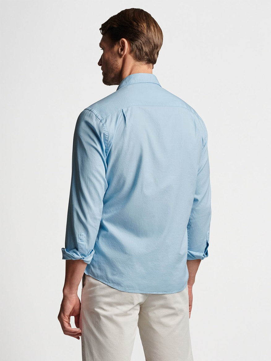 Man wearing a Peter Millar Sojourn Garment-Dyed Cotton Sport Shirt in Blue Frost with a tailored fit and beige pants viewed from the back.