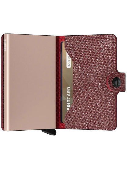 Bronze-colored smartphone with a Secrid Miniwallet Sparkle in Red attached to the back featuring RFID protection.