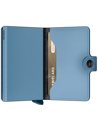 A blue Secrid Miniwallet Yard Powder in Sky Blue open to reveal a single gold credit card with RFID protection.