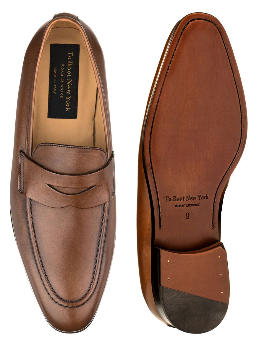 To Boot New York Tesoro in Brandy, a pair of premium calf leather penny loafers crafted by Italian artisans, with one shoe displaying the top view and the other showing the sole.