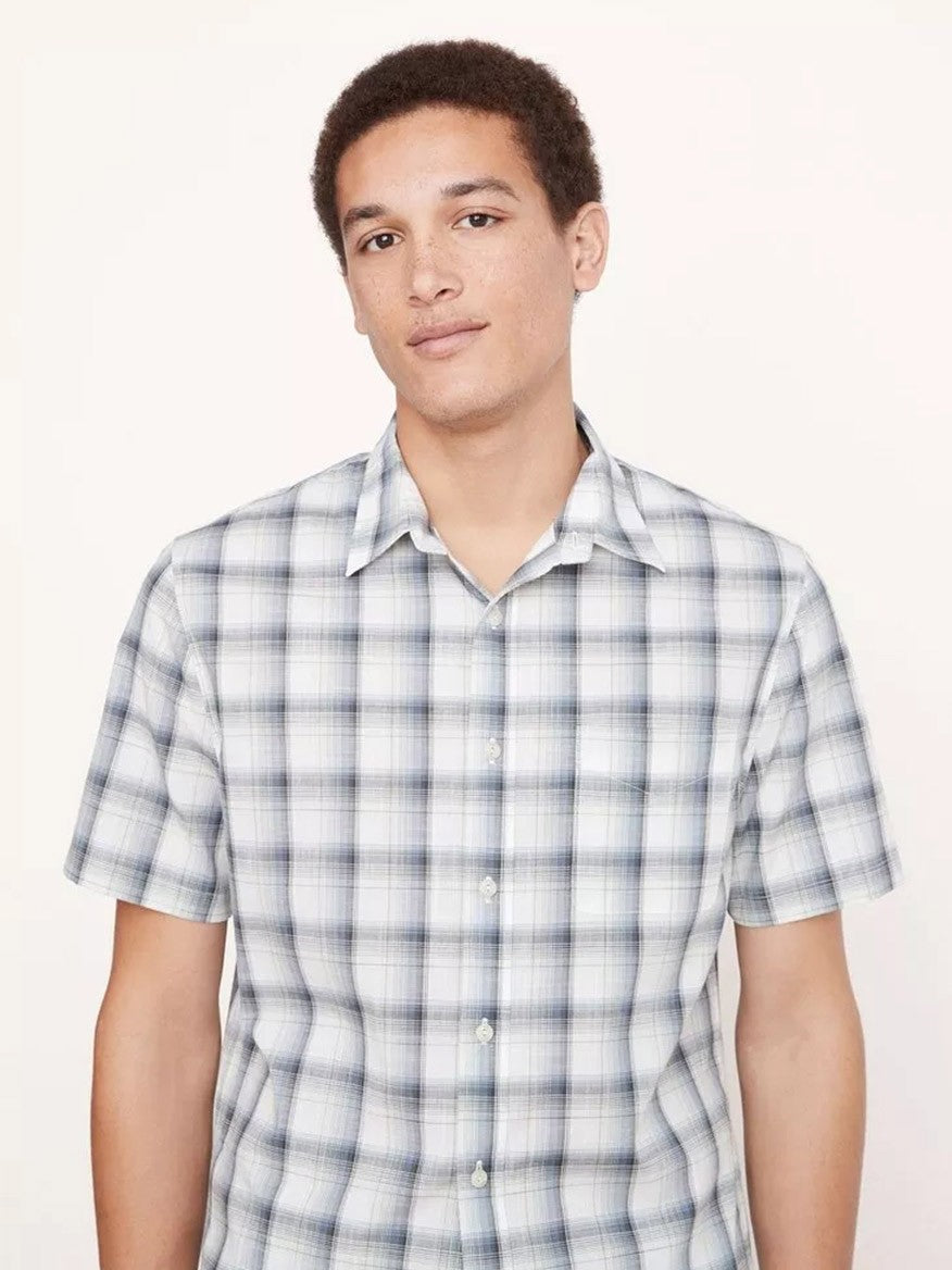 A person stands against a plain background, wearing the Vince Atwater Plaid Short Sleeve Shirt in Celery, which is made from pure cotton.