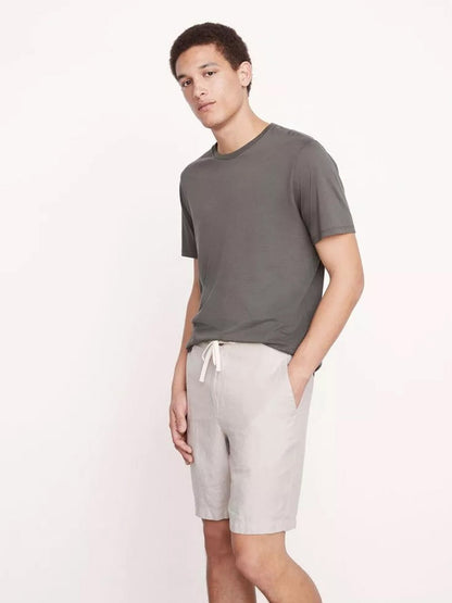 A young man posing in a casual gray t-shirt and Vince Lightweight Hemp Short in Beach Sand with a drawstring closure.