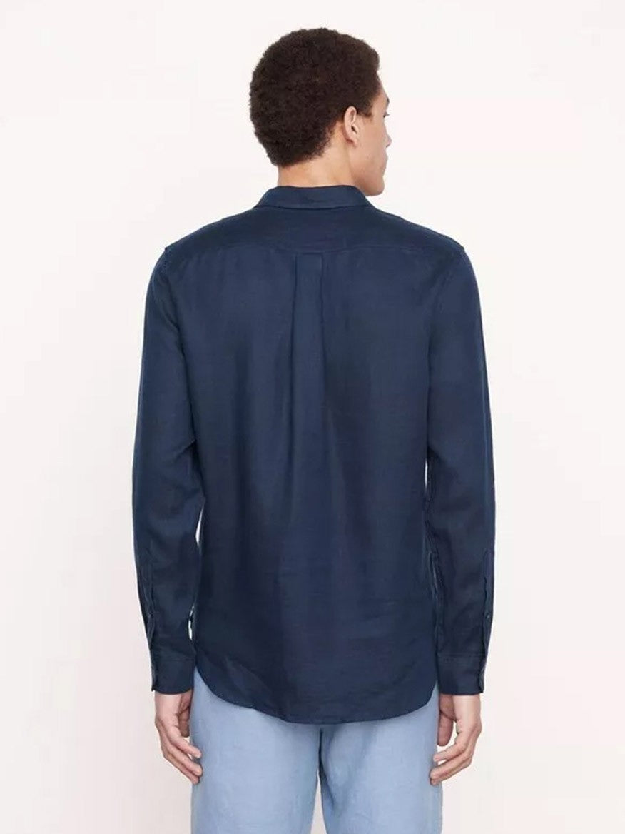 Man standing with his back to the camera wearing a Vince Linen Long Sleeve Shirt in Coastal, designed for warm-weather, and light blue pants.