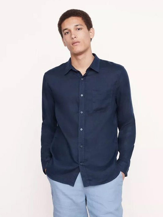 Young man in a Vince Linen Long Sleeve Shirt in Coastal and light blue trousers, designed for warm-weather with cooling linen, standing against a plain background.