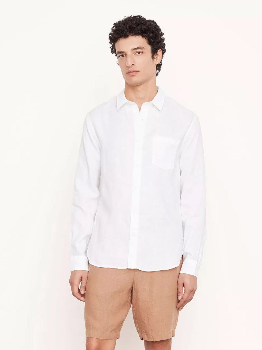 A person with short curly hair is wearing the Vince Linen Long Sleeve in Optic White and tan shorts, standing against a plain light background.