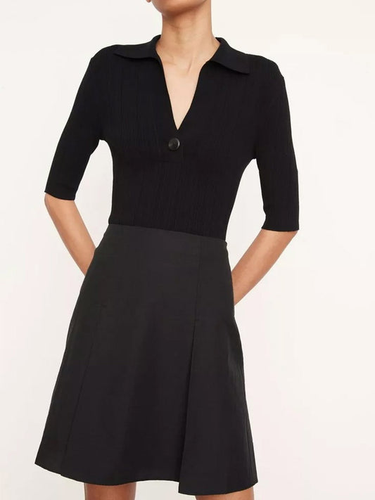 A person stands against a plain background, effortlessly stylish in the Vince Pleated Short Skirt in black. The design exudes sophistication with its clean lines and classic look.