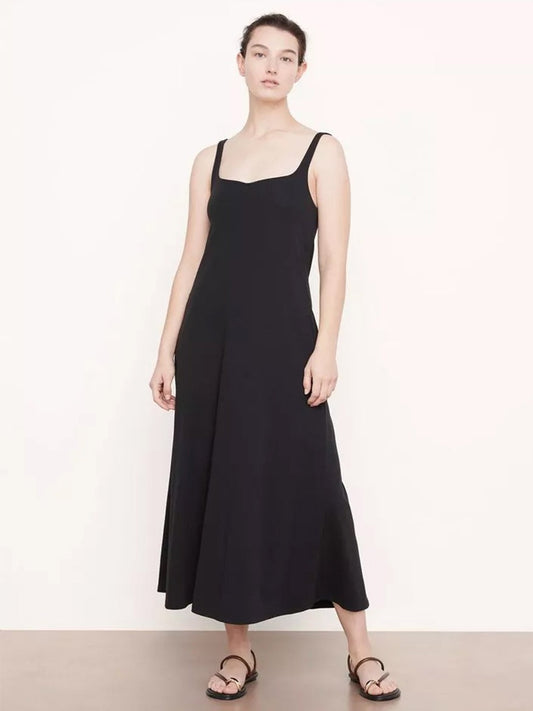 A woman in Vince's Paneled Trapeze Dress in Black with a center back zipper and flat sandals stands against a plain background.