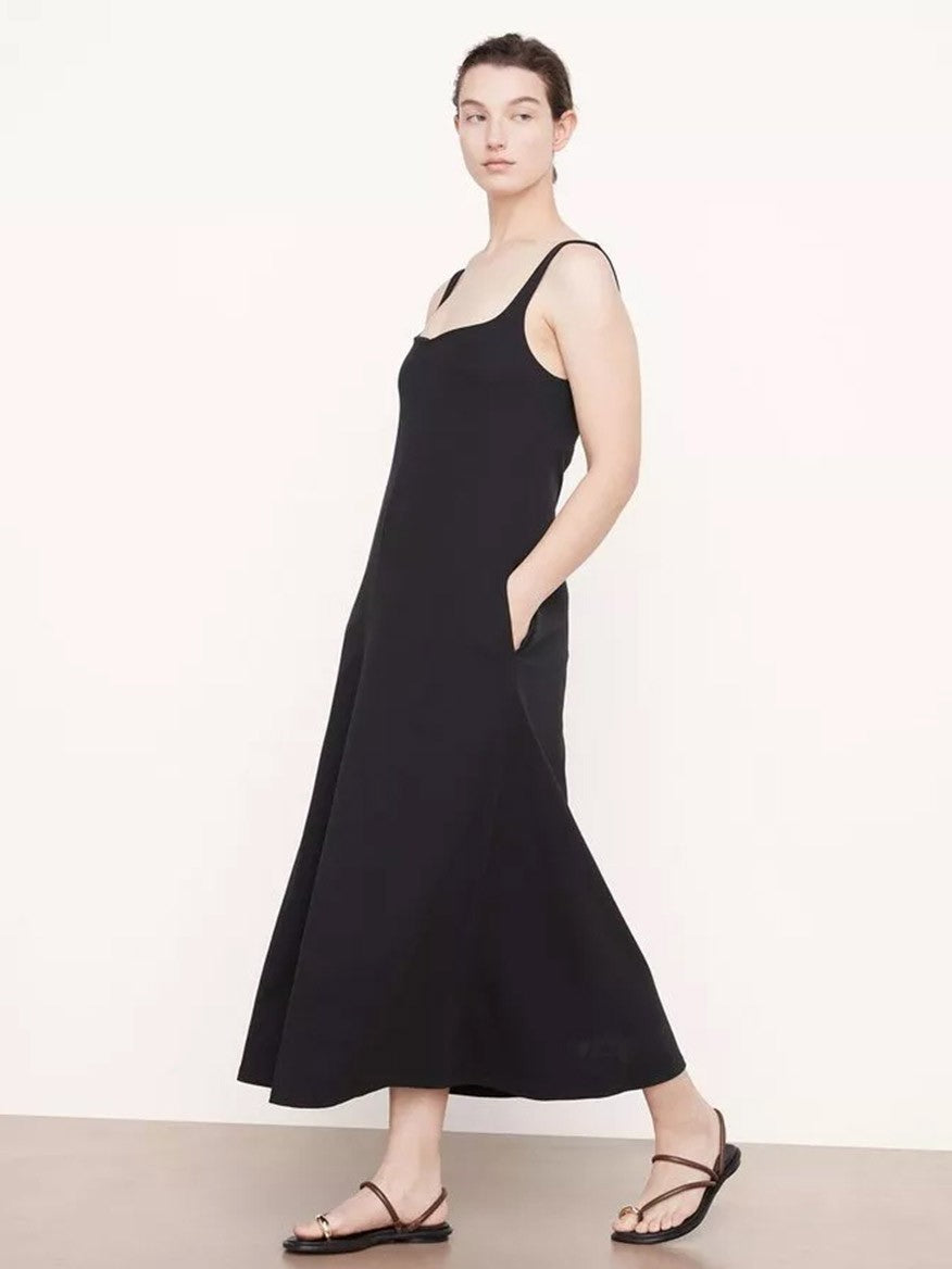 A woman models Vince's Paneled Trapeze Dress in Black with flat sandals, standing against a plain light background.