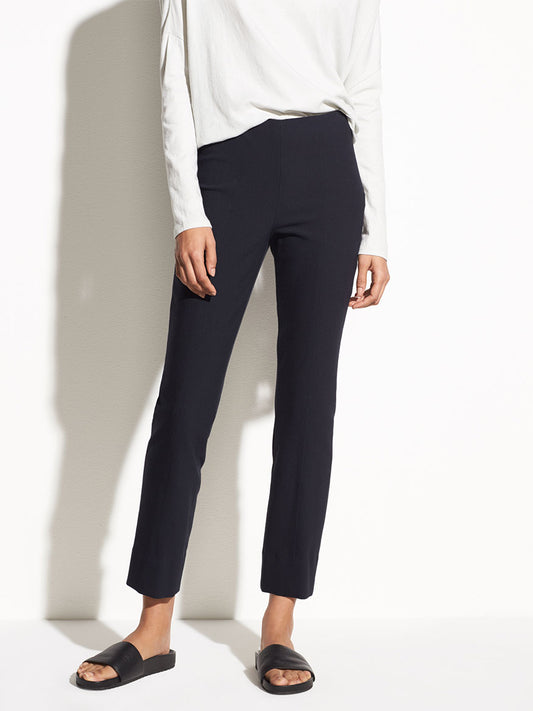 Woman wearing Vince Stitch Front Seam Ponte Legging in Coastal with an elasticated waistband and a white top with black sandals, standing against a light background.