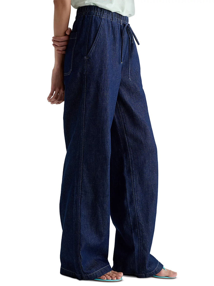Model wearing the AG Jeans Adria Cinched Jean Low-Rise Wide Leg in Napa, featuring a linen blend denim, elastic drawstring waistband, low-rise fit, side pockets, and visible seam details.