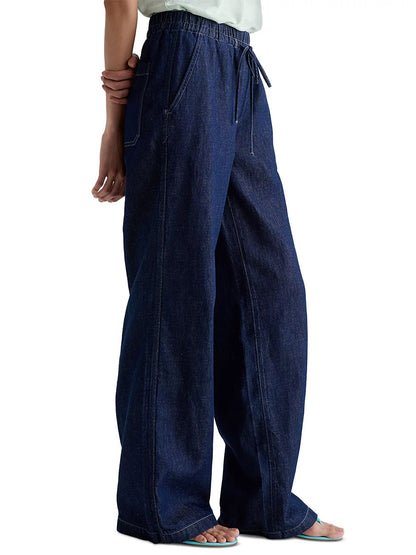 Model wearing the AG Jeans Adria Cinched Jean Low-Rise Wide Leg in Napa, featuring a linen blend denim, elastic drawstring waistband, low-rise fit, side pockets, and visible seam details.