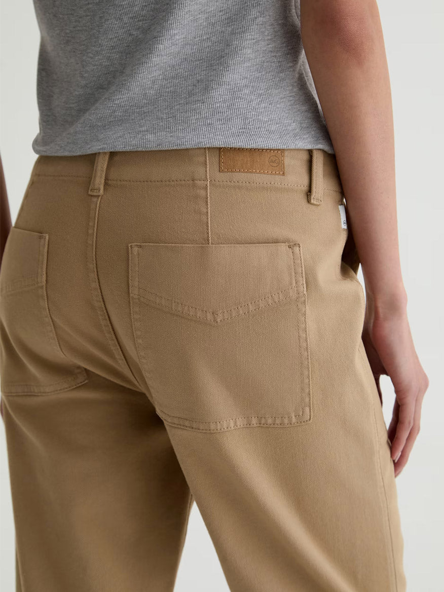 Model shown from the back wearing AG Jeans Analeigh Mid-Rise Utility Pant in Khaki Sand with a gray top, highlighting the pant’s rear pockets and waistband.