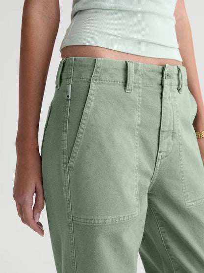 Model shown from mid-torso to mid-thigh wearing the AG Jeans Analeigh Mid-Rise Utility Pant in Sulfur Faded Moss, styled with a matching light green ribbed tank top.