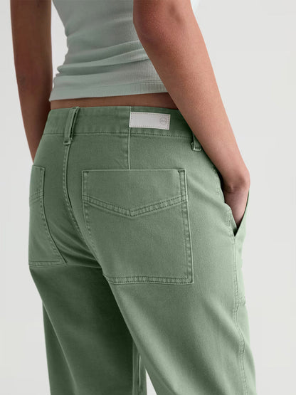 Someone wearing the AG Jeans Analeigh Mid-Rise Utility Pant in Sulfur Faded Moss and a light green ribbed top, shown from the back with one hand in their pocket.