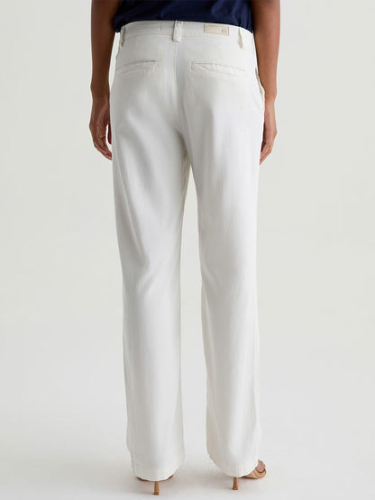 Person wearing AG Jeans Caden Straight Leg Trouser in Powder (white, tailored fit) with a dark top, shown from the back and standing on a light-colored floor.