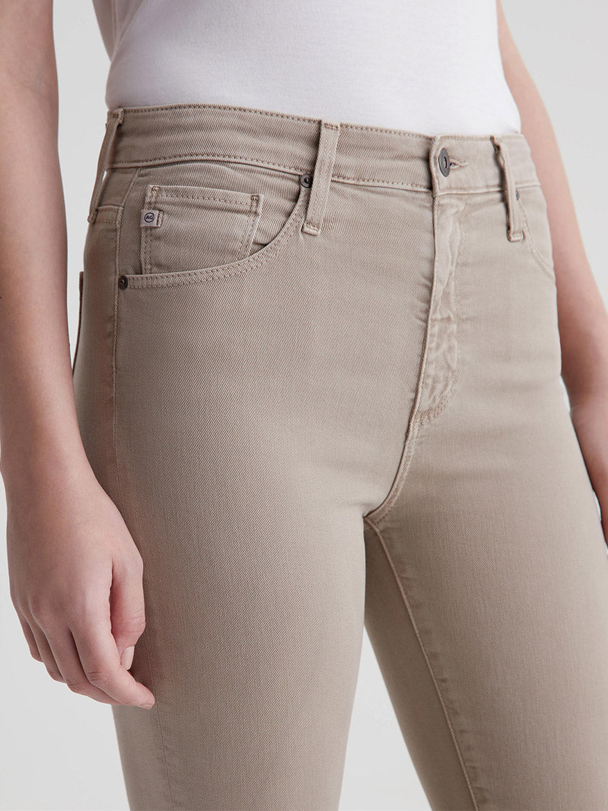 Close-up of a person wearing AG Jeans Farrah Boot Crop in Sulfur Desert Taupe bootcut jeans with a focus on the pocket detail.