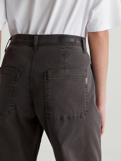 Rear view of a person in a white t-shirt and AG Jeans Fiona High-Rise Barrel in Sulfur Misty Grey, standing against a plain background, with visible back pockets.